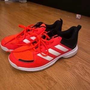 Röda Adidas sneakers - Snygga röda Adidas sneakers med vita ränder och svarta detaljer. Skorna har en bekväm passform och är perfekta för träning eller vardagsbruk. De har en slitstark sula och snörning för optimal passform. Köpta för 800kr