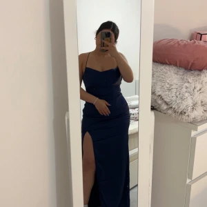 Mörkblå långklänning med smala axelband - Elegant mörkblå långklänning med smala axelband och en stilren design. Perfekt för en kväll ute eller en speciell tillställning såsom balen. Klänningen har en mjuk och följsam passform som framhäver figuren. Den är köpt från Nelly för 900kr och har använts en kväll🫶🏼