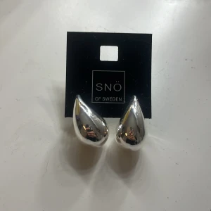 Silverörhängen från Snö of Sweden - Snygga droppformade silverörhängen från Snö of Sweden. Perfekta för att ge en elegant touch till din outfit. De har en blank yta som fångar ljuset fint. Aldrig använda, köpt för 290kr