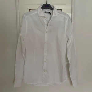 Vit J.Lindeberg skjorta  - Klassisk vit skjorta från J.Lindeberg. Perfekt för en stilren look. Passar med kavaj. 
