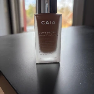 CAIA Dewy Drops Serum Foundation - Säljer en flaska CAIA Dewy Drops Serum Foundation i nyansen 20C. Denna foundation ger en naturlig och daggig finish och kommer i en stilren flaska med silverfärgad pump. Perfekt för en fräsch och återfuktad look. Endast testad!
