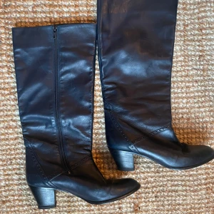 Mörkblå skinnstövlar från Peter Kaiser - Snygga svarta stövlar i skinn från Peter Kaiser med dragkedja på sidan. Skorna är en mörk blå nästan svart färg och har en låg klack.