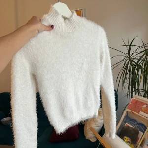 Vit fluffig tröja - Säljer en supermjuk och fluffig vit tröja med polokrage. Perfekt för kyliga dagar när du vill känna dig både varm och stilren. Tröjan har långa ärmar och en ribbad kant vid halsen. Ett måste i garderoben för den som älskar komfort och stil! 🤍