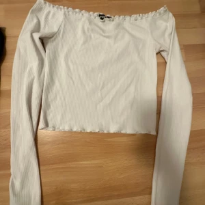 Svart offshoulder topp - Snygg svart offshoulder topp med ribbad struktur och långa ärmar. Perfekt för en stilren look. Den vita är i S och den svarta i XS