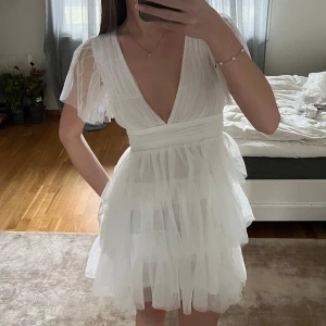 Vit kortklänning med volanger - Säljer en söt vit kortklänning med volanger och v-ringad design.🤍Ej använd, endast provad. Nypris 500kr.