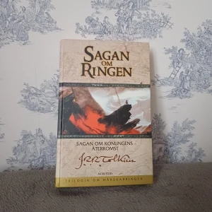 Sagan om konungens återkomst - Säljer boken 'Sagan om konungens återkomst' av J.R.R. Tolkien, del av 'Trilogin om härskarringen'. Boken har ett omslag med en dramatisk illustration och är utgiven av Norstedts. Perfekt för fantasyälskare och samlare! Har en liten färgfläck