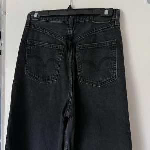Svarta jeans från Levi’s - Snygga svarta jeans med hög midja och raka ben från märket Levi’s. Klassisk femficksdesign med silverfärgade nitar och knapp. Perfekta för en stilren look. 💜 Önskar du veta exakta mått? Tveka inte att höra av dig!