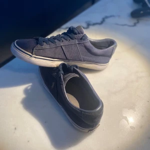 Blå sneakers från Polo - Snygga blå sneakers från Polo med klassisk design och snörning. Skorna har en vit sula och en diskret logga på sidan. Perfekta för en avslappnad stil.