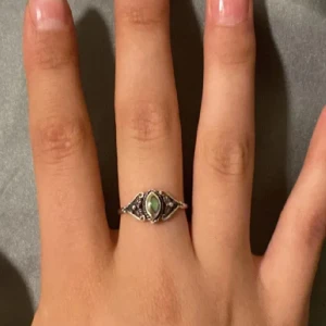 Silverring med grön sten - Elegant silverring med en vacker grön sten i centrum. Ringen har detaljerade mönster på sidorna som ger den en unik och stilfull look. Perfekt för att ge en touch av färg och elegans till din stil.