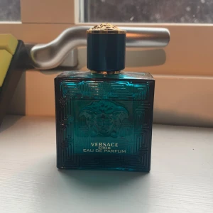 Versace Eros Eau de Parfum herrparfym - Säljer en lyxig herrparfym, Versace Eros Eau de Parfum. Gissar på att det är typ 42 ml kvar. Hör gärna byte. Flaskan är fyrkantig i turkost glas med guldiga detaljer och ett elegant mönster samt Medusa-huvudet på framsidan. Perfekt för dig som gillar exklusiva dofter. Box medföljer