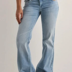 Low Waist Bootcut Stitch Jeans - Snygga ljusblå jeans med bootcut passform och dubbla knappar i midjan. Jeansen har klassisk femficksdesign och är tillverkade i denim med lätt tvättad look. Perfekta för en avslappnad och trendig stil. Gillar inte den så jag säljer