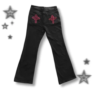 Svarta bootcut jeans med röda korsdetaljer - ☆ Svarta högmidjade bootcut jeans med röda broderade kors på bakfickorna, nästan oanvända! Mått: Midja 37cm, ben insida 78 cm, lår 22 cm, ben längst ner 26 cm ☆