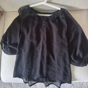 Svart trekvarts puffiga armar blus - Säljer denna snygga svarta blusen som är supersnygg med ett linne under men även utan om man vill. Vissa av knapparna har tappat lite färg men kan nog enkelt fixas men annars är det något jag själv inte lägger märke till. Är i storlek S men lös passform så funkar nog på M med.💞
