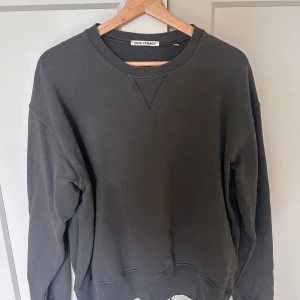 Mörkgrå sweatshirt från Our Legacy - Nypris 2 240 kr!🤩En stilren mörkgrå sweatshirt från Our Legacy med klassisk rund halsringning och ribbade muddar. Tröjan har en avslappnad passform och är tillverkad i mjuk bomull, perfekt för en enkel och snygg look. 