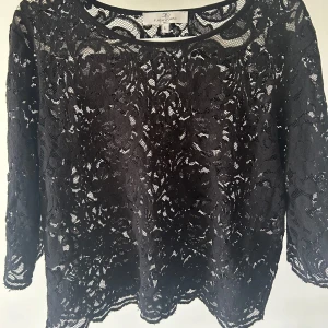 Svart spetsblus från Flash Woman - Säljer en svart blus från Flash Woman i storlek L men sitter mer som en S! Blusen är helt i spets med vackert mönster och har trekvartsärm. Perfekt för dig som vill ha en elegant och stilren topp med fina detaljer.💞