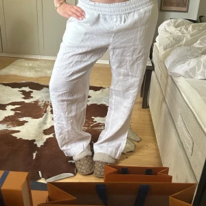 Vita linnebyxor med resårmidja - Säljer ett par vita linnebyxor med avslappnad passform och resår i midjan. Byxorna har raka ben och sidfickor, perfekta för en luftig och bekväm stil. Passar lika bra till strandhäng som till vardags.