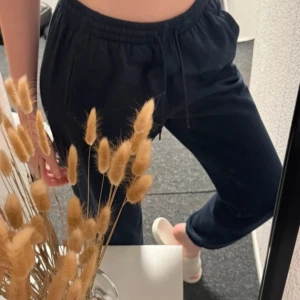 Mörkblå mjukisbyxor från mywear - Mörkblå mjukisbyxor från mywear med resår och dragsko i midjan. Byxorna har en avslappnad passform och är perfekta för en chill stil. Mjukt material och enkla att matcha med sneakers eller tofflor.