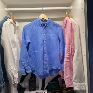 Blå skjorta från Polo Ralph Lauren - Säljer en klassisk blå skjorta från Polo Ralph Lauren med gul broderad logga på bröstet. Skjortan har lång ärm, knappar framtill, krage och gjort av linne. Nypris ligger runt 1200-1400. Storlek 10-12 år 150-160cm. Perfekt nu inför sommarn.                                                                              Skriv vid frågor, först till kvarn 🤗🤝