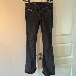 Svarta jeansbyxor från Diesel - Säljer ett par svarta jeansbyxor från Diesel med klassisk femficksdesign och diskreta slitningar. Byxorna har raka ben och normal passform, med Diesel-logga på fickan fram och bak. Perfekta för en stilren vardagslook. Midjemått: 36 cm, innerbenslängd: 80 cm