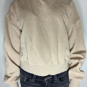 Beige sweatshirt från H&M Divided - Enkel och stilren beige sweatshirt från H&M Divided. Tröjan har en loose passform med långa ärmar och ribbade muddar vid ärmslut och midja. Säljer på grund av att den är för liten för mig. Pris kan diskuteras❤️