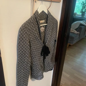 Mönstrad stickad jacka Odd Molly - Jag har storlek xs/s och den passar mig.Snygg stickad jacka från Odd Molly i svart och grått med rutig känsla och broderad detalj. Jackan har lång ärm, knytband framtill och ett unikt mönster över hela plagget. Perfekt för dig som vill ha något både bekvämt och stilrent.
