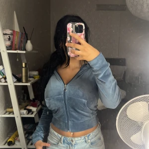 Blå croppad velourjacka med dragkedja - Säljer en blå croppad jacka i mjuk velour med lång ärm och dragkedja framtill. Jackan har en snygg, tight passform och en cool ringdetalj på dragkedjan. Perfekt för dig som gillar en chill men trendig stil.