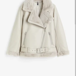 Beige teddyjacka med bälte och dragkedja - Snygg beige teddyjacka från H&M köpt för 670 med mjukt foder och detaljer i fuskpäls. Jackan har bred krage, dragkedja i sned modell, två fickor med dragkedja och bälte i midjan. Perfekt för kalla dagar när du vill vara både varm och trendig. Obs passar från L till XXL