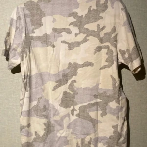 Beige camo t-shirt från WESC - Snygg t-shirt från WESC i storlek L med beige och grått camouflage-mönster. T-shirten har korta ärmar och rund hals. Materialet är mjuk bomull och trycket med WESC-loggan på bröstet ger en cool streetkänsla.