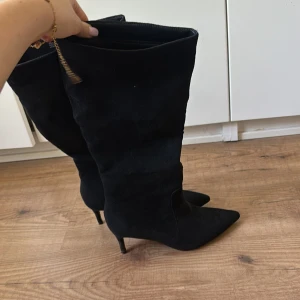 Svarta mockastövlar med spetsig tå strl 37 - Snygga svarta stövlar i mocka med spetsig tå och smal klack. Köpt från boohoo i storlek 37. Använda en gång
