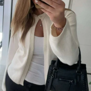 Beigekofta med rund hals - Säljer en stilren beige kofta med rund hals och knäppning framtill. Koftan har långa ärmar och är gjord i ett mjukt stickat material som känns skönt mot huden. Perfekt att slänga över en topp för en clean och fräsch look.