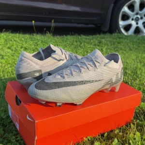 Nike Mercurial Air Zoom fotbollsskor grå - Nike Mercurial Air Zoom fotbollsskor i ljusgrått med svarta detaljer och stor Swoosh-logga. Jag säljer pågrund av att de är för stora för mig. De är limiterade fotbollsskor som jag säljer för över 1500 kr billigare. Andvända max 5 gånger