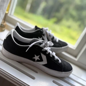 Svarta Converse sneakers med vit sula - Svarta Converse sneakers med vit sula och klassisk stjärnlogga på sidan. Skorna har vita snören och detaljer, låg profil och rund tå. Ovandelen är i mocka för en snygg och stilren look. Perfekta för dig som gillar streetstyle.