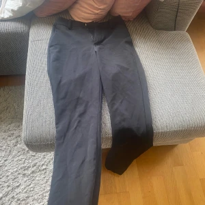 Svarta bikbok kostymbyxor med raka ben högmidjade - Snygga svarta kostymbyxor med klassisk rak passform och bälteshällor. Byxorna har diskreta fickor bak och är perfekta för en clean och stilren look.byxorna är i jätte bra kvalitet och storlek 34 Villket är xs