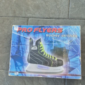 Pro Flyers hockeyskridskor svart/grön - Snygga hockeyskridskor från Pro Flyers med svart ovandel, vita sömmar och coola neongröna snören. Klassisk form med högt skaft för bra stöd och vit sula. Perfekta för isen när du vill sticka ut med stil.