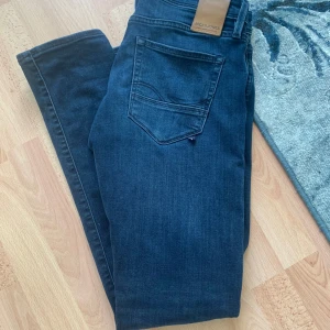 Jack & Jones Slim Glenn jeans blå - Mörkblå jeans från Jack & Jones, modell Slim Glenn. Snygg slim fit med klassisk femficksdesign och diskret tvätt. Tillverkade i stretchig bomullsdenim för skön passform. Perfekta för dig som gillar en grisch siluett och stilren look.