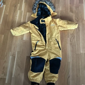 Vinteroveroll gul o svart  - Hu o svart vinteroveroll med tre fickor, har en luva o är nästan ny, bra att ha på kalla viterdagat när barnet vill leka med snön. Kan diskutera om priset 