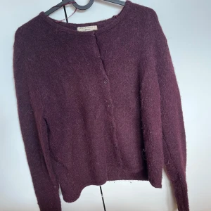 Vinröd kofta från Gina Tricot - Mysig vinröd kofta från Gina Tricot i stickad ullmix. Klassisk rund halsringning, knäppning framtill med små knappar och långärmad modell. Perfekt för lager-på-lager och chill höst- eller vinterstil.