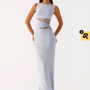 Ljusblå långklänning med spetsdetalj - Supersnygg ljusblå långklänning med ärmlös design och transparent spets i midjan som ger en cool cut-out effekt. Klänningen har en slank siluett och ett omlottliknande tyg över spetsen. Så snygg blå färg perfekt till sommar och fest 🥰 storlek 40 men passar 36-40. Endast använd 1 gång och köpt i sommar