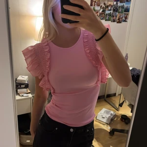 Rosa volangtopp med rynkade axlar - Rosa topp med volanger och detaljer längs axlarna. Använd ca 2ggr. Storlek xs men passar även mig som vanligtvis bär s. 80kr💕