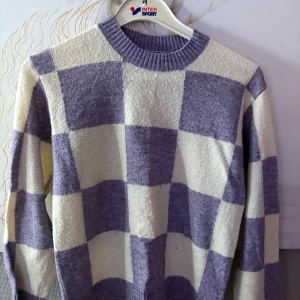 Lila och vit rutig tröja Lindex - Supermysig stickad tröja från Lindex i storlek 158/164. Tröjan har ett stort rutigt mönster i lila och vitt, rund halsringning och ribbade muddar. Perfekt för dig som gillar en chill och trendig stil.