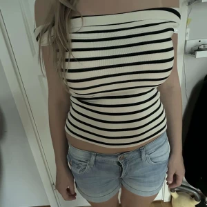 Randig offshoulder tubtopp - Säljer en snygg offshoulder tubtopp med svarta och vita ränder. Stickat material.