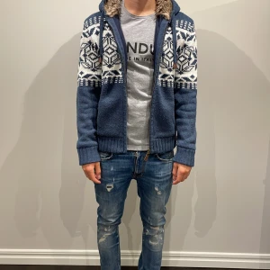 Blå stickad Pier one hoodie med mönster - Mysig blå stickad hoddie med unika mönster som är perfekt för lite kyligare dagar. Hoodien är från märket pier one och nypris ligger på ca 800 kronor. Hoodien är sparsamt använd och i perfekt skick och därför av mitt pris 699. Priset kan dock diskuteras vid snabb affär.