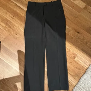 Grå kostymbyxor  - Snygga grå kostymbyxor med medelhög midja och en klassisk rak passform. Perfekta för en stilren look. Byxorna har diskreta fickor och en smidig dragkedja framtill. Innerbenslängd 81cm. Byxorna är nya, använda max 2 gånger. (Köpta på bikbok för 599kr, helt slutsålda på deras hemsida)