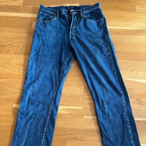 Blå straight jeans från GAP, 32x34 - Klassiska blå jeans från GAP i modellen Original Straight. Jeansen har fem fickor, raka ben och snygga kontrastsömmar. Tillverkade i robust denim med en tidlös look som funkar till allt. Perfekt passform och enkel stil.