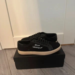 Helt nya Saint Laurent sneakers  - Säljer ett par svarta Saint Laurent sneakers i modellen Court Classic SL/06, med handskriven “SAINT LAURENT” logga på sidan. Klassiska och stilrena skor med en lyxig men avslappnad känsla. Passar perfekt till både vardag och lite finare tillfällen. Nypris: 6900 kr. Säljes p.g.a. att de inte kommer till användning.