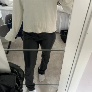 Svarta raka byxor i skinnimitation - Säljer ett par svarta byxor i skinnimitation med rak passform. Byxorna har klassisk midja och stilren look, perfekta för dig som vill ha en edgy vibe. Snygga att styla med både sneakers och boots.