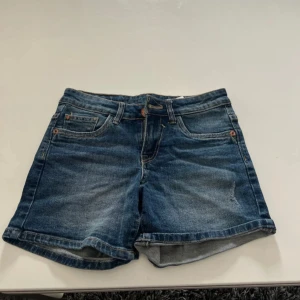Blå jeansshorts från Garcia Jeans - Snygga blå jeansshorts från Garcia Jeans med klassisk femficksmodell och uppvikta benslut. Shortsen har normal passform och är perfekta för varma dagar. Tillverkade i slitstarkt denimtyg med cool tvättad look och detaljerade sömmar.