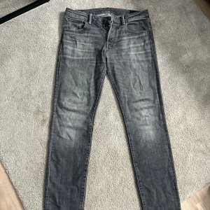 Grå slim straight jeans 33/34 - Säljer ett par grå jeans i modellen Slim Straight 33/34. Jeansen har klassisk femficksdesign, raka ben och snyggt slitna detaljer framtill. Perfekt för dig som gillar lite tajtare jeans.