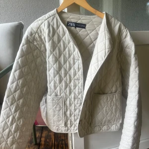 Quiltad beige jacka från Zara - Quiltad jacka från Zara i beige med stora fickor framtill. Jackan har ett rakt, loose fit och är tillverkad i ett mjukt bomullsmaterial. Perfekt för lager-på-lager och ger en chill vibe till din outfit. Det står strl L men skulle säga att den sitter som en S-M