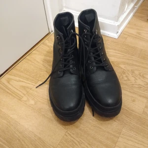 Svarta boots från Zara  - Chunky svarta boots från Zara med grov sula och snörning framtill. Skorna är i skinnimitation och har en rund tå. Perfekta för dig som gillar en edgy och stilren look till höst och vinter.
